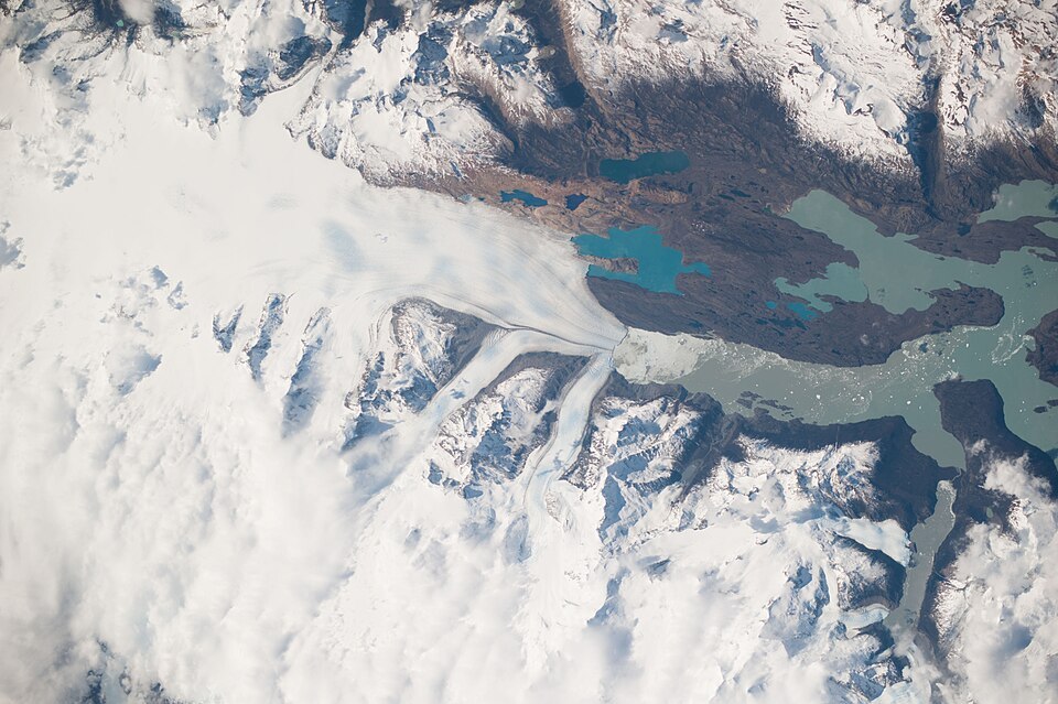 Upsala Glacier Retreat and Patagonia Icefield are featured in this image photographed by an Expedition 37 crew member on the International Space Station.
This photograph highlights the snout of the Upsala Glacier (49.88S 73.3W) on the Argentine side of the North Patagonian Icefield. Ice flow in this glacier (white mass, left) is from the north (left). Dark lines of rocky moraine within the ice give a sense of the slow ice flow from left to right. A smaller side glacier joins Upsala at the present-day ice front the wall from which masses of ice periodically collapse into Lake Argentino.
In this